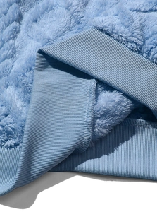 Dettaglio ravvicinato del tessuto in pile sherpa azzurro con orlo elastico a coste