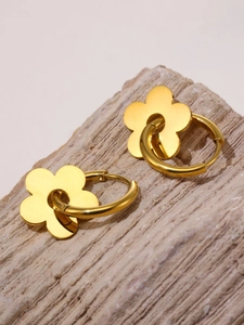 Close-up of 18k gold-plated flower charm hoop earrings on a light textured stone surface