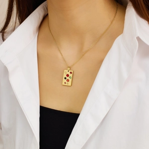 Primer plano de collar dorado con colgante rectangular decorado con piedras de colores