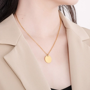 Collier doré en acier inoxydable avec pendentif disque rond porté par un mannequin