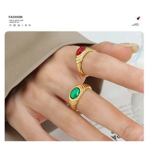 Close-up of vintage gold rings with red and green gemstones and textured bands