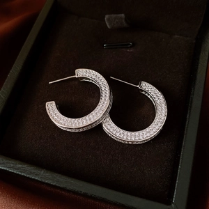 Close-up of silver C-shaped hoop earrings with micro-set white zircon in a jewelry box