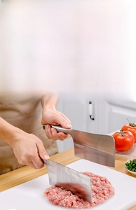 Close-up of white PE cutting board with stainless steel knife slicing meat in a kitchen
