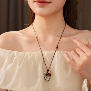Detail of bohemian heart pendant necklace with cross inlay and colorful ethnic beads