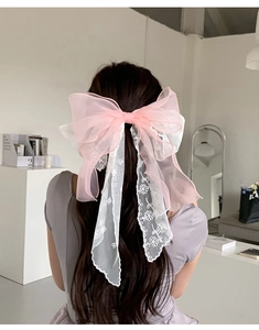Pink tulle bow hair clip with white floral lace embroidery on a long flowing ribbon