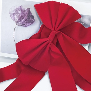 Close-up of large red velvet Christmas ribbon bow for festive cabinet and fireplace decor