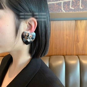 Polished silver heart earrings with square zircon stone worn by a model in lifestyle setting