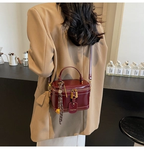 Burgundy box bag shown on model back with elegant gold zipper and metal charm