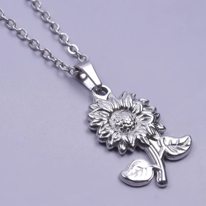 Close-up of a silver stainless steel sunflower pendant necklace on a purple background