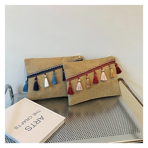 Detail view of woven jute envelope clutch with ethnic tassels and metal zipper closure