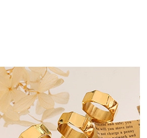 Detailed view of a geometric gold ring featuring smooth metallic mirror reflections
