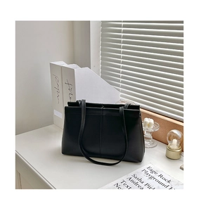 Close-up of a black minimalist tote bag on a desk with artistic shutter light and shadows
