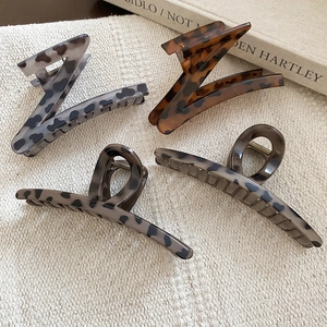 Flat lay of retro leopard print resin hair claws in Z-shape on soft linen background