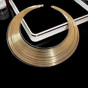 Close-up of a minimalist multi-layer gold metal wire choker on a sleek black surface
