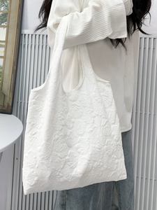 Detail showing 3D embossed rose pattern on white tote bag with textured surface