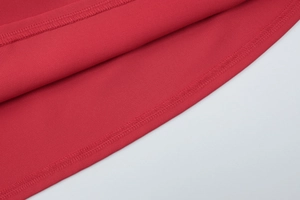 Detailed close-up of red chiffon dress hem showing precise double-needle stitching quality