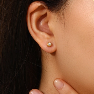 Close-up of minimalist gold earring with a white pearl on earlobe for jewelry detail