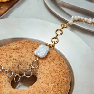 Detail of baroque pearl necklace with mixed gold and silver chains on a creative background