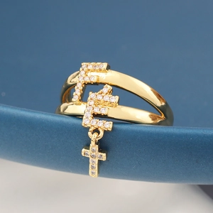 Macro detail of a gold pin ring with sparkling zircon letter F and cross charms
