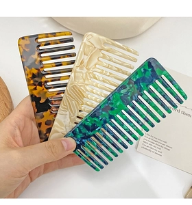 Close-up of wide-tooth acetate hair combs in tortoiseshell and pearl patterns