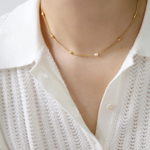 Close-up of minimalist freshwater pearl necklace on a white knit collar blouse