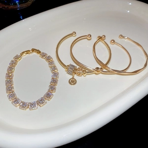 Gros plan de bracelets dorés sertis de zircons avec un pendentif en forme de cœur