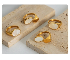 Detail of adjustable gold-plated stainless steel rings featuring white shell inlays on stone