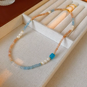 Detailed view of the square aquamarine bead and pearls on a vintage beaded necklace