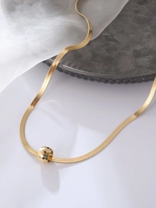 Detalle de un collar de cadena de serpiente dorada con un colgante de cuenta facetada