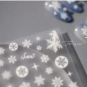 Makroaufnahme von 3D-Präge-Schneeflocken-Nagelstickern mit Snow-Schriftzug