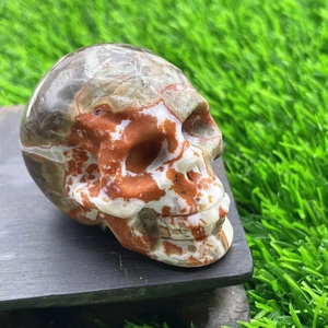 Detailed close-up of a 5cm carved multi-colored agate crystal skull on a dark wood base
