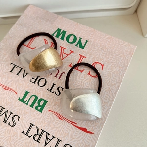 Close-up of minimalist gold and silver hair ties with acrylic charms on a vintage book