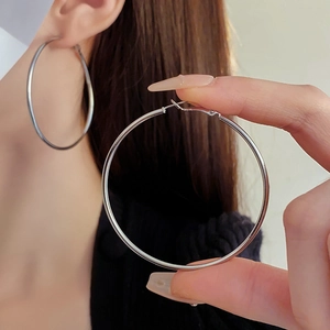 Macro detail of large polished silver hoop earrings showing smooth metallic texture and shine