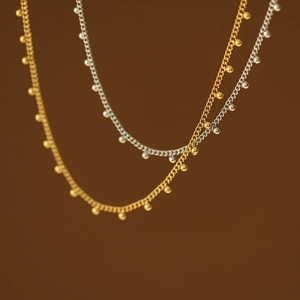 Macro shot of minimalist gold and silver beaded necklaces with ball pendants on thin chains