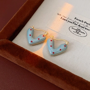 Macro shot of blue enamel heart earrings with red dots in a luxury jewelry gift box