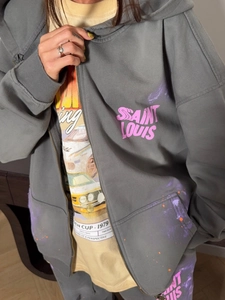 Détail d'un sweat à capuche gris style urbain avec lettrage Saint Louis vintage