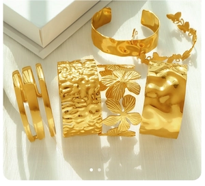 Macro detail of gold hammered texture and hollow floral patterns on adjustable bangles