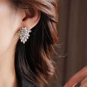 Macro shot of a sparkling silver flower stud earring with marquise-cut crystals on ear