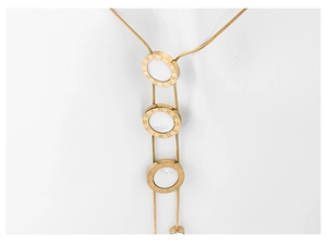 Detailed close-up of layered gold necklace with Roman numeral engraved circular pendants