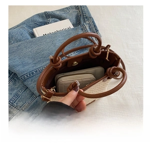 Straw woven bucket bag with leather trim showing interior capacity for phone and wallet