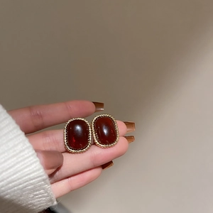 Close-up of vintage oval red resin stud earrings with textured gold-tone borders