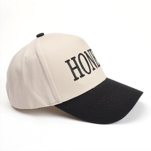 Detail view of contrast stitching and black letter embroidery on beige baseball cap