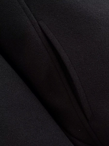 Macro view of black wool fabric texture and detailed pocket stitching on the fashion coat