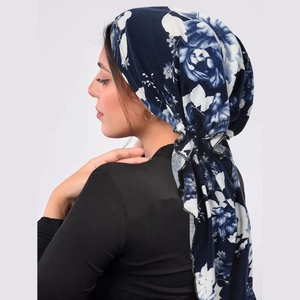 Detail of navy blue turban hat with white floral print shown on female model profile