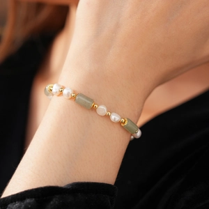 Detail of bamboo shaped jade and pearl bracelet worn on wrist with gold spacers
