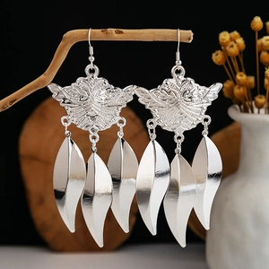 Silver bohemian style long leaf tassel earrings displayed on a rustic wooden stand