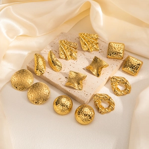 Detailed view of golden geometric earrings featuring textured surfaces on stone pedestal