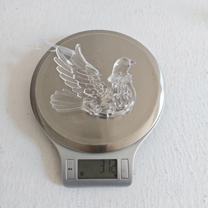 Macro detail of clear acrylic bird ornament showing 31.2g weight on digital scale