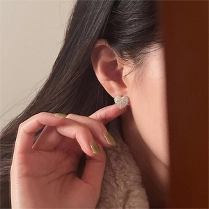 Close-up of a model wearing heart-shaped silver earrings with sparkling pavé cubic zirconia