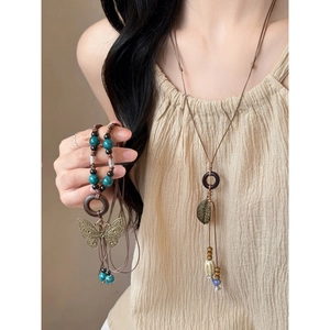 Detail of vintage bohemian necklace with wooden rings, bronze leaf, and butterfly pendant